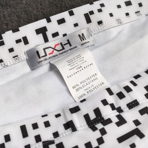 Detail view of UXH brand tag and size M label on black and white geometric swimwear