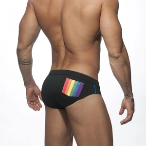 Detail view of men's black swim trunks featuring rainbow stripe pocket on back