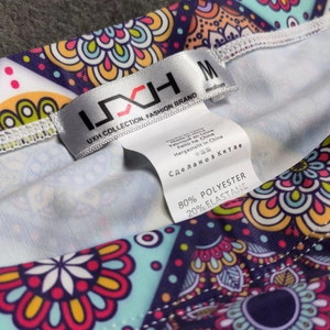 Detail of multi-color mandala print waist with 80% polyester label on men's swim trunks