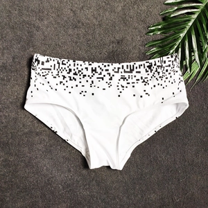 Flat lay of white men's swim trunks with black geometric pixel pattern on waistband