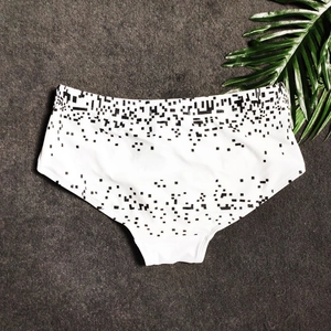 Close-up of white swim trunks with black pixel mosaic print and elastic fabric texture