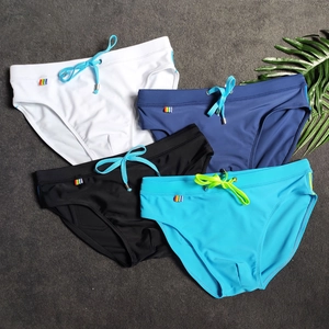 Flat lay of men's quick-dry swim briefs in four colors with drawstrings on a stone surface