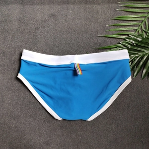 Flat lay of blue men's swim briefs with white trim and rainbow ribbon detail
