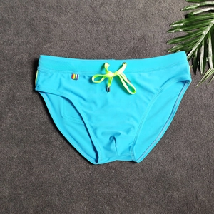 Detail of blue men's swim briefs featuring neon yellow drawstring and rainbow stripe tag