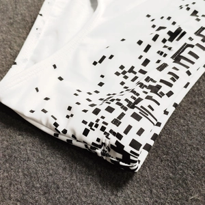Detail of men's white swim trunks showing geometric pixel pattern and elastic seam stitching