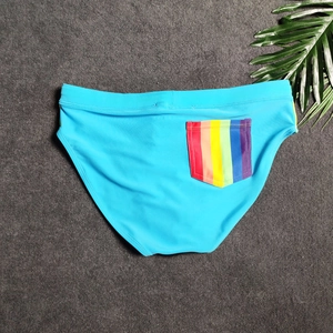 Detail of light blue men's swim briefs featuring a vibrant rainbow pocket on the back side