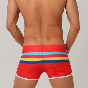 Detail of men's red swim trunks featuring colorful side stripes and white piping trim