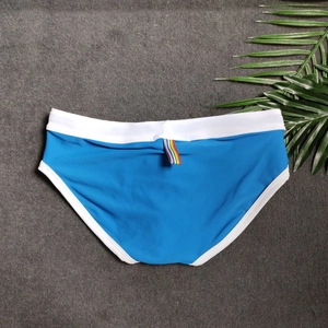Detail of royal blue men's swim briefs with white trim and rainbow tab on the waistband
