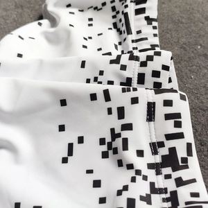 Macro detail of men's white swim trunks showing pixelated black tech pattern and stitching