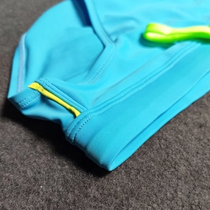 Detail of blue men's swim briefs with lime green drawstring and reinforced stitching