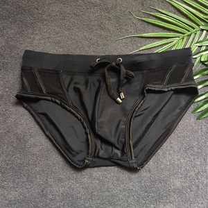 Detail of men's black swim briefs with mesh side panels and silver-tipped drawstrings