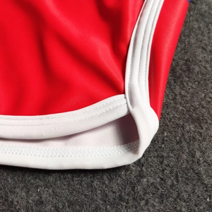 Detail of red athletic shorts with white trim and reinforced flatlock stitching detail