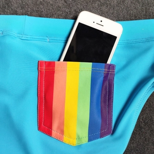 Detail of blue men's swim trunks with rainbow stripe pocket and phone storage