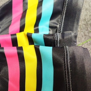 Detail view of quick-dry swim briefs featuring vibrant pink yellow and cyan vertical stripes