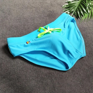 Close-up of bright blue men's swim briefs with lime green drawstring and rainbow tag