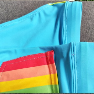 Detailed close-up of blue swim briefs with rainbow stripes and high-quality stitching