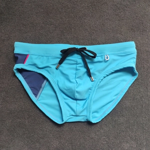 Detail of blue men's swim briefs with contrast paneling, drawstring, and metal tips