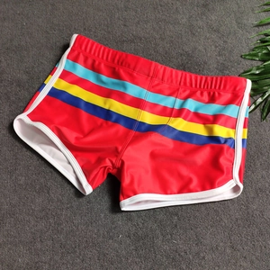 Flat lay of red men's swim trunks featuring colorful side stripes and white elastic piping