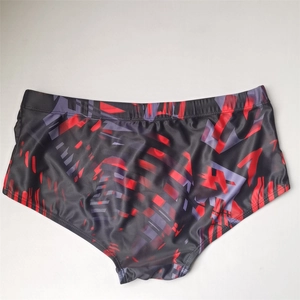 Detail of men's quick-dry swim trunks with abstract red and black geometric print