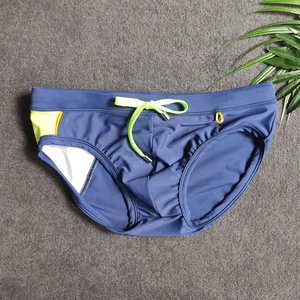 Flat lay of navy blue swim briefs featuring neon yellow drawstring and side accents