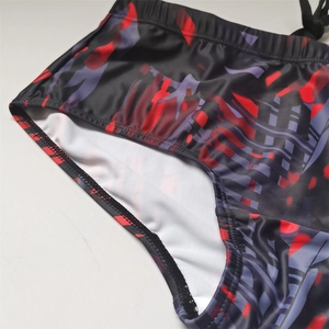Close-up of men's swim trunks featuring red abstract print and adjustable drawstring waist
