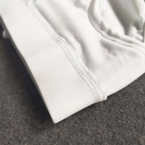 Detailed close-up of white mesh fabric and double-stitched seams on men's swimwear