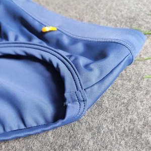 Macro shot of navy ribbed swimwear fabric with orange drawstring buckle and stitching