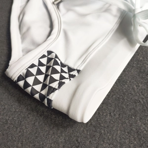 Macro detail of white swim briefs with geometric pattern side panels and drawstring