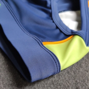 Macro view of men's bikini swimwear showing stitching and elastic patchwork fabric