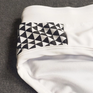 Close-up of side seams and geometric triangle pattern on men's white swim briefs