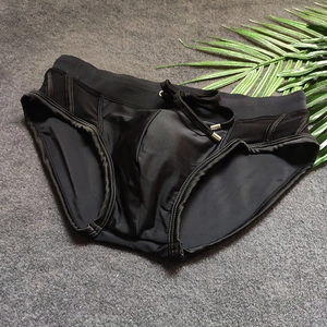 Detail view of men's black swim trunks with mesh patchwork and adjustable drawstring cords