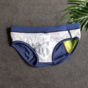 Detailed close-up of navy blue and white patchwork men's swim briefs on a textured mat