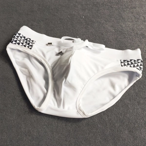Detail of white men's swim briefs featuring side geometric patterns and metal-tipped drawstrings