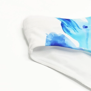 Detailed macro view of blue ink floral print on white swimwear with double-stitched edges