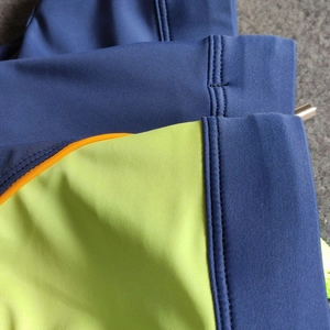 Detailed close-up of navy and neon green swimwear with orange stitching and flatlock seams