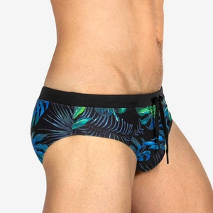 Men's swim briefs with gradient tropical leaf print and drawstring waistband on model