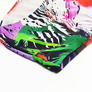 Detail of flatlock stitching and vibrant colorful coconut tree pattern on swim shorts