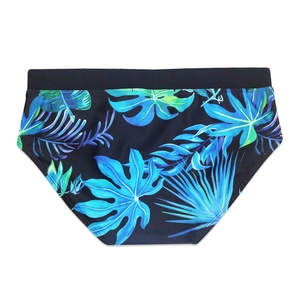 Detail view of men's swimming trunks featuring vibrant blue and green tropical leaf patterns