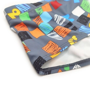 Detailed view of colorful geometric block print and stitching on mens swimming trunks
