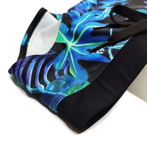 Detail of men's swim briefs showing leaf print, elastic waistband, and adjustable drawstrings