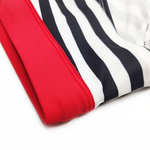 Detailed close-up of striped red and black swimwear fabric with elastic stitching