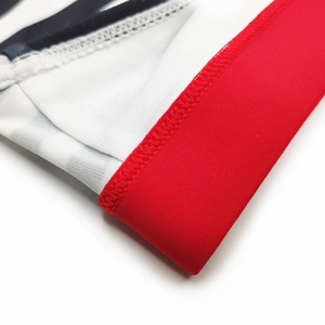 Macro detail of red elastic waistband and stitching on striped men's swim briefs
