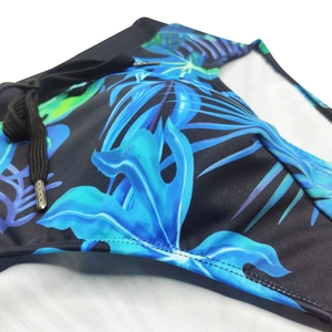 Detail of men's tropical leaf swim trunks showing elastic waistband and metal drawstring