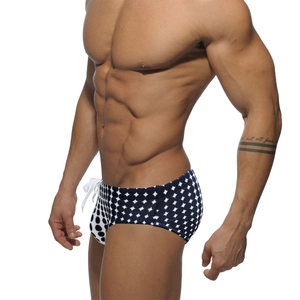 Macro detail of men's swim trunks featuring black and white geometric dot print and side drawstring