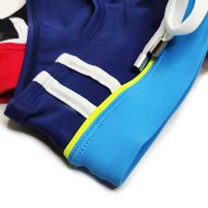 Macro detail of men's swim briefs featuring colorful panels and metal-tipped drawstrings