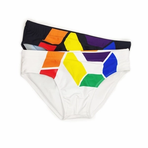 Flat lay detail of black and white men's swim briefs featuring colorful geometric patterns