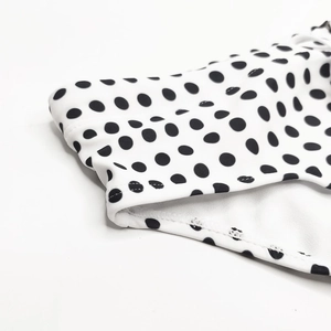 Detailed close-up of white swimwear fabric with black polka dots and high-quality stitching