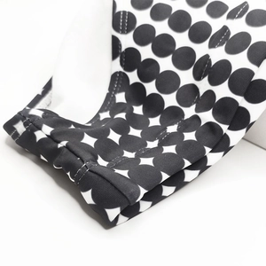 Close-up of black and white polka dot swimwear fabric showing high-quality double stitching