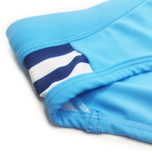 Close-up of sky blue swim briefs featuring navy and white striped side panel detail