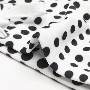 Close-up of white swim briefs with black polka dots, featuring a white drawstring and metal eyelets